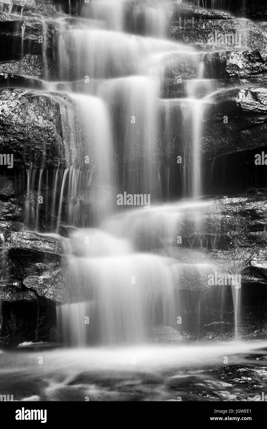 Black white blurred stream of water flowing down the sandstone rocks in Australian central coast rainforest near Gosford - Somersby falls. Stock Photo