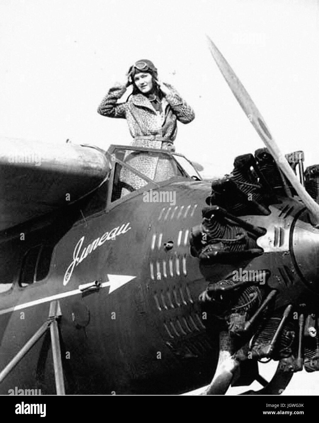 Woman in a cheetah print coat, aviator helmet and goggles, standing in the cockpit of pontoon plane, probably Washington State Stock Photo