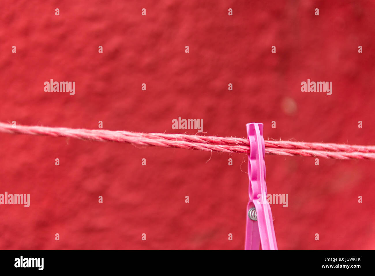 Vintage view of pink Clothes peg pinned to a bench with red wall in a