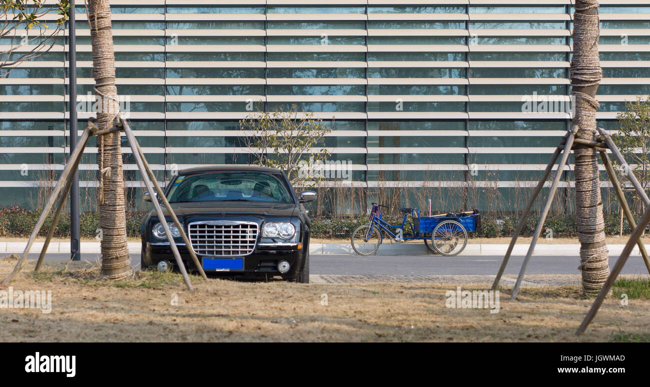Executive car and worker's tricycle parked outside building of Xi'an Jiaotong-Liverpool University. Suzhou, China Stock Photo