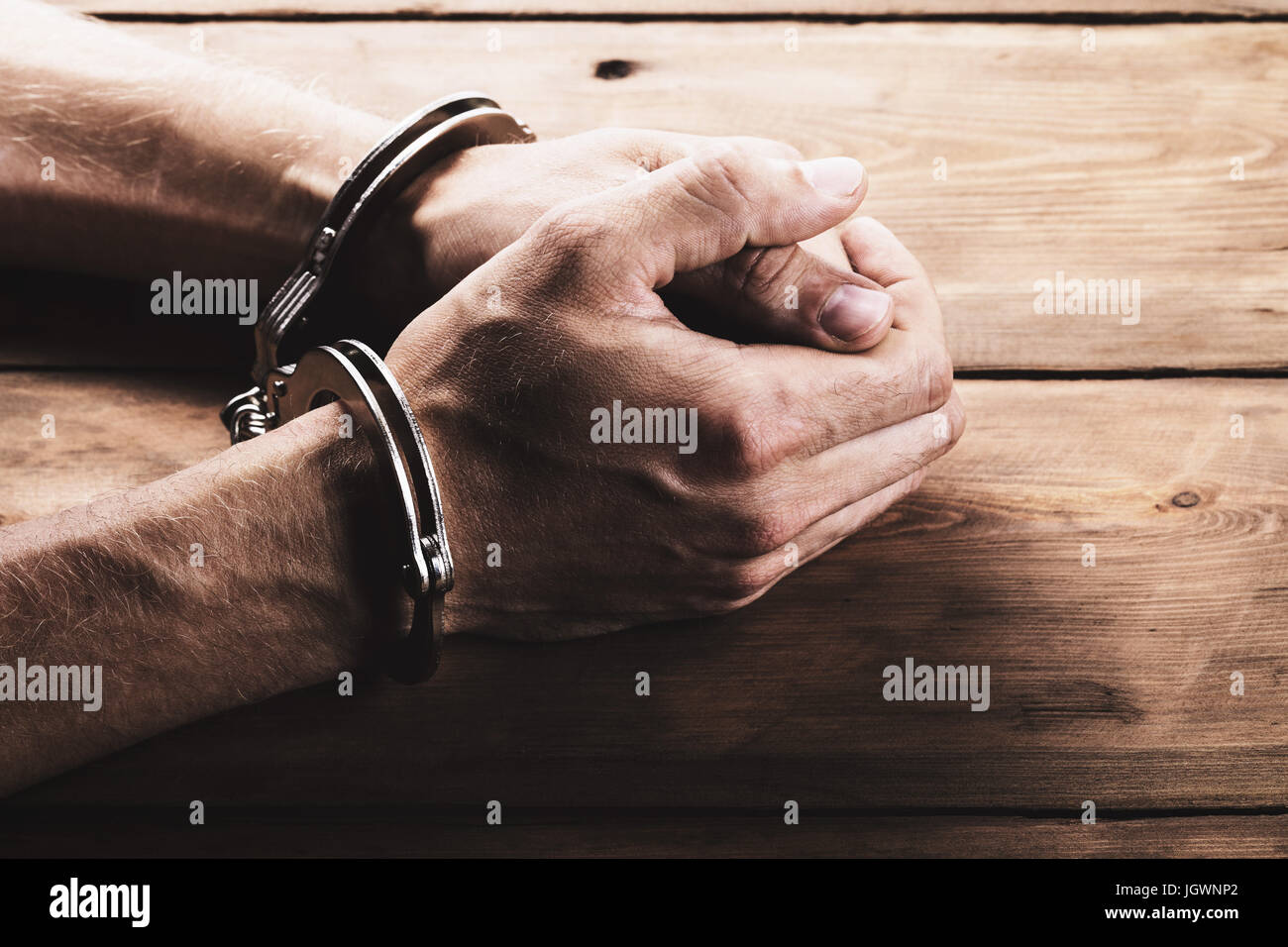 hands with handcuffs on the table Stock Photo