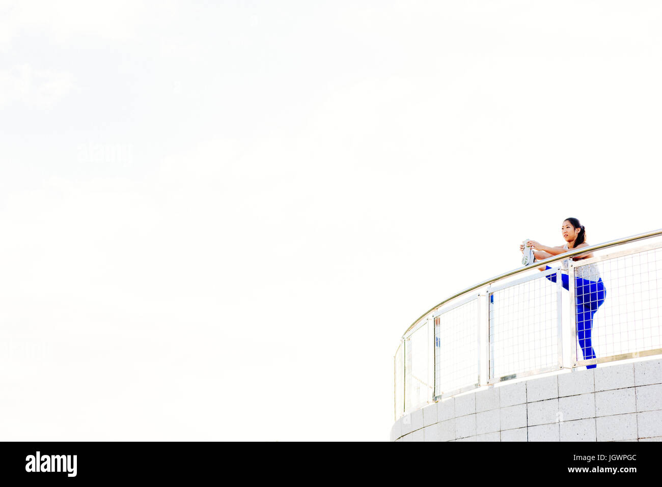 Young woman exercising outdoors, stretching leg on railing, South Point Park, Miami Beach, Florida, USA Stock Photo