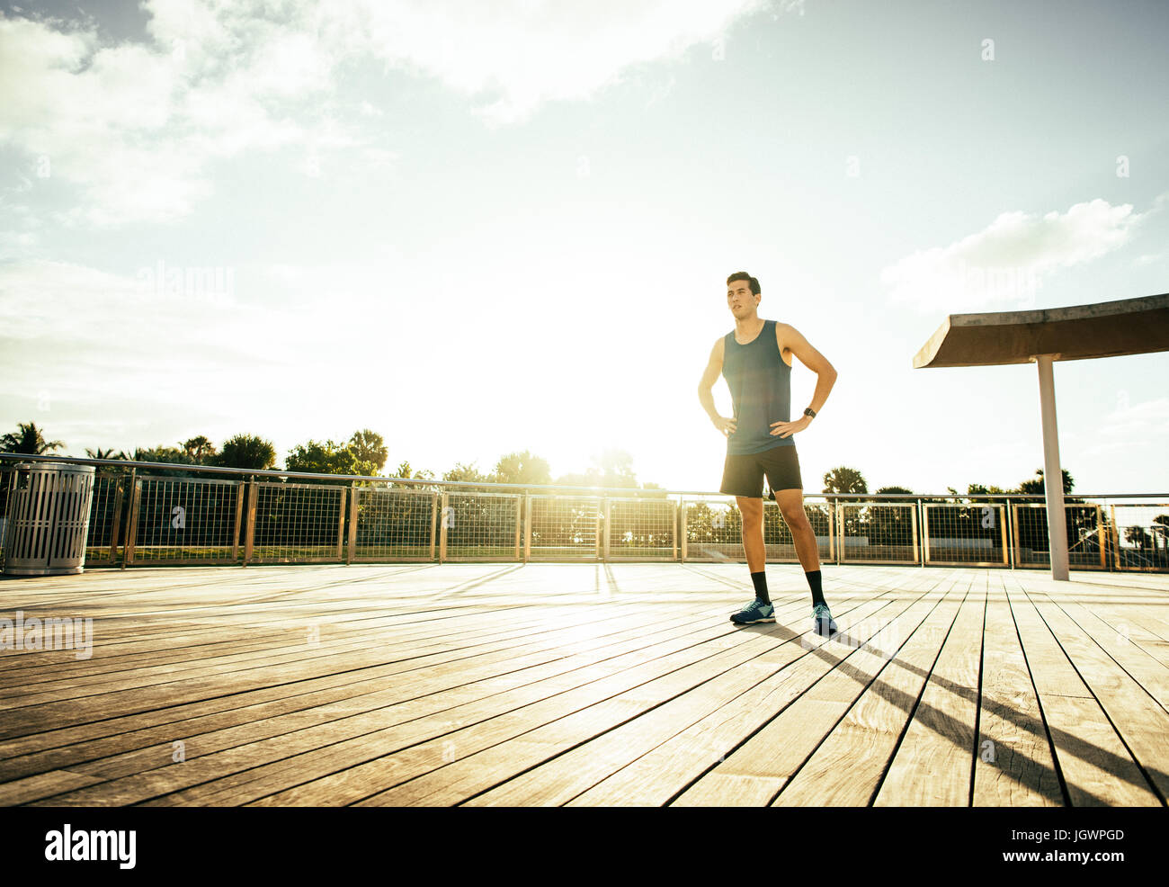 Young man wearing sports clothing, standing outdoors, hands on hips Stock Photo