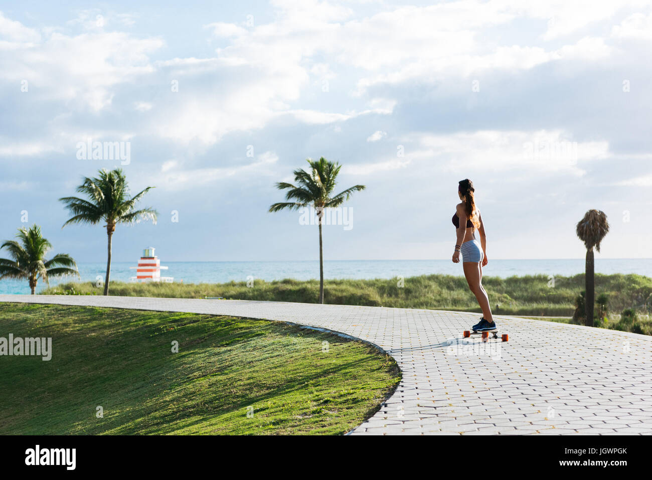 Young woman skateboarding in park, rear view, South Point Park, Miami Beach, Florida, USA Stock Photo