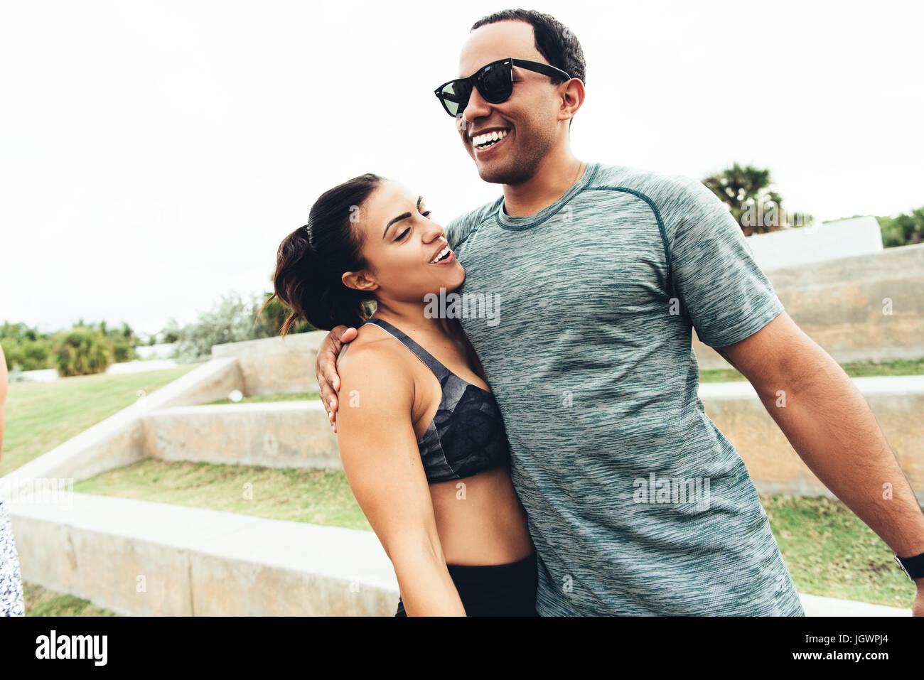 Young man and woman wearing sports clothing, outdoors, hugging, South Point Park, Miami Beach, Florida, USA Stock Photo