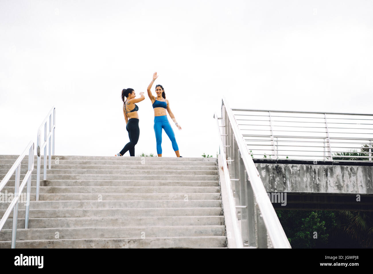 Two young women at top of steps, celebrating workout, South Point Park, Miami Beach, Florida, USA Stock Photo