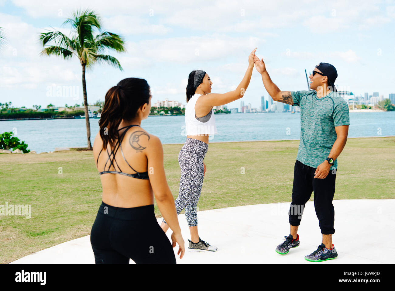 Young woman celebrating workout with personal trainer, South Point Park, Miami Beach, Florida, USA Stock Photo