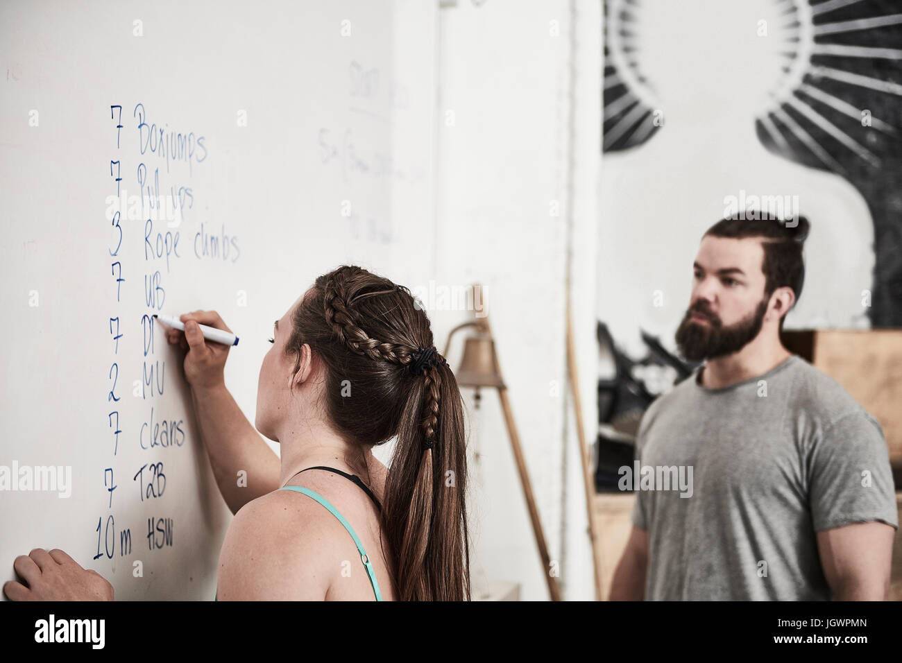 Fitness instructor writing on whiteboard in cross training gym Stock Photo