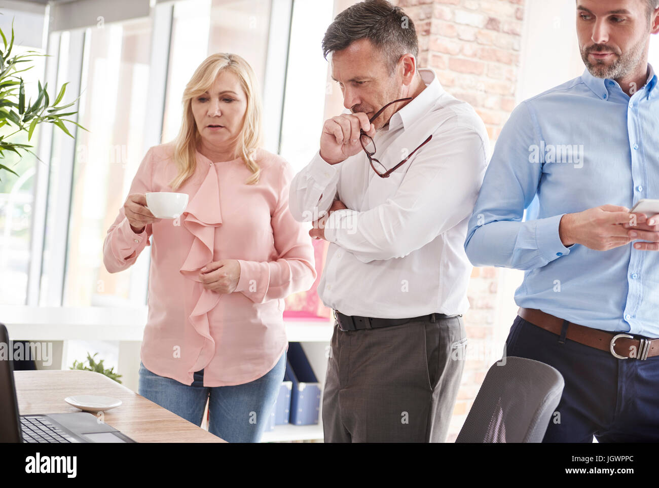 Colleagues in office with laptop having discussion Stock Photo - Alamy