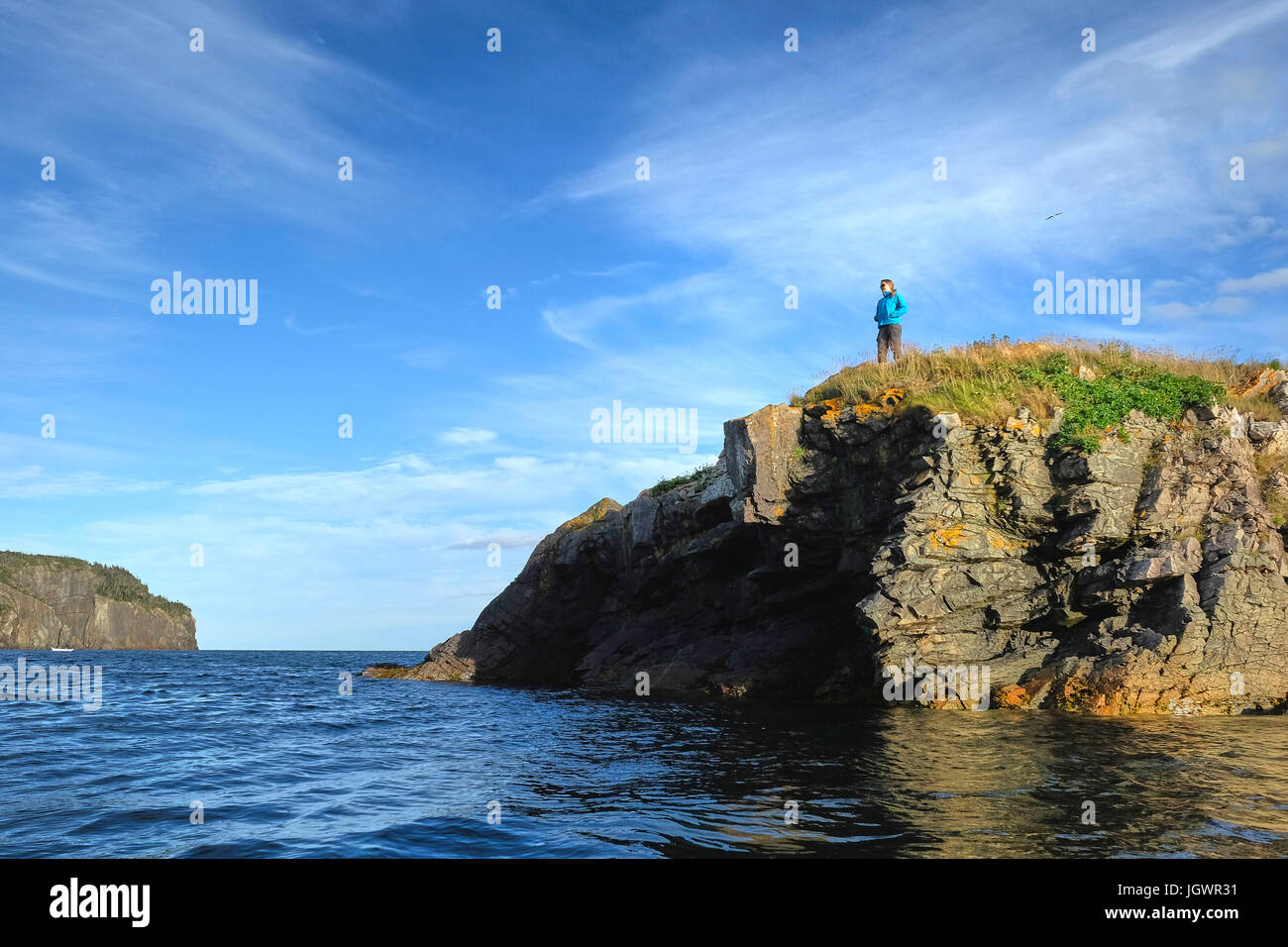 Mid adult woman looking out from coastal cliff, St John's, Newfoundland, Canada Stock Photo