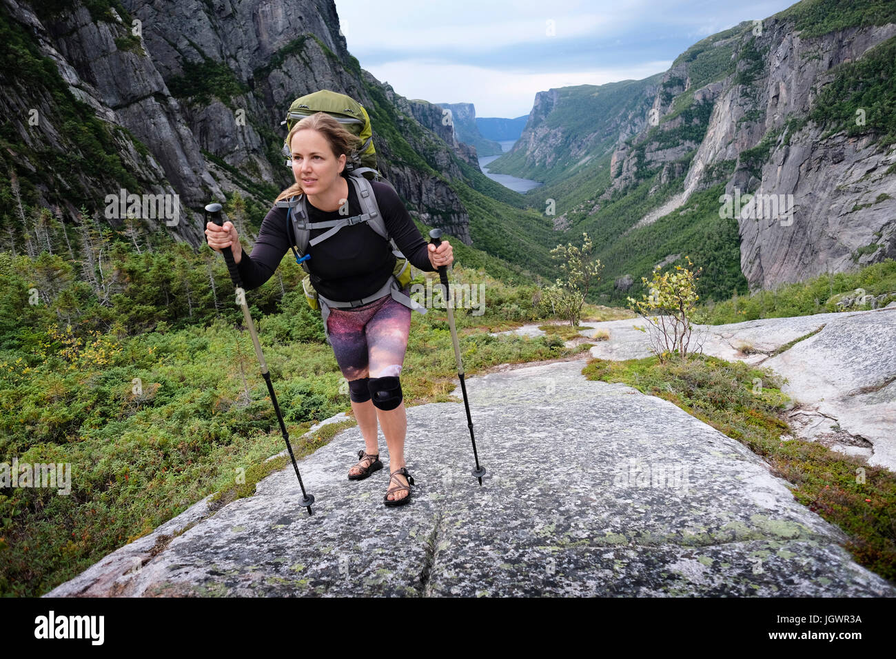 Mid adult woman hiking up rocky valley, Gros Morne National Park, Newfoundland, Canada Stock Photo