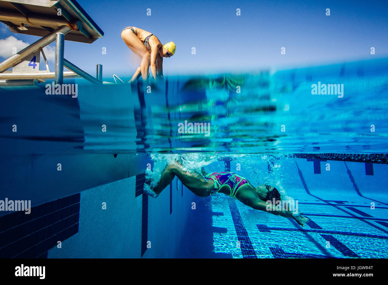 Swimmer on diving board and swimmer in pool Stock Photo