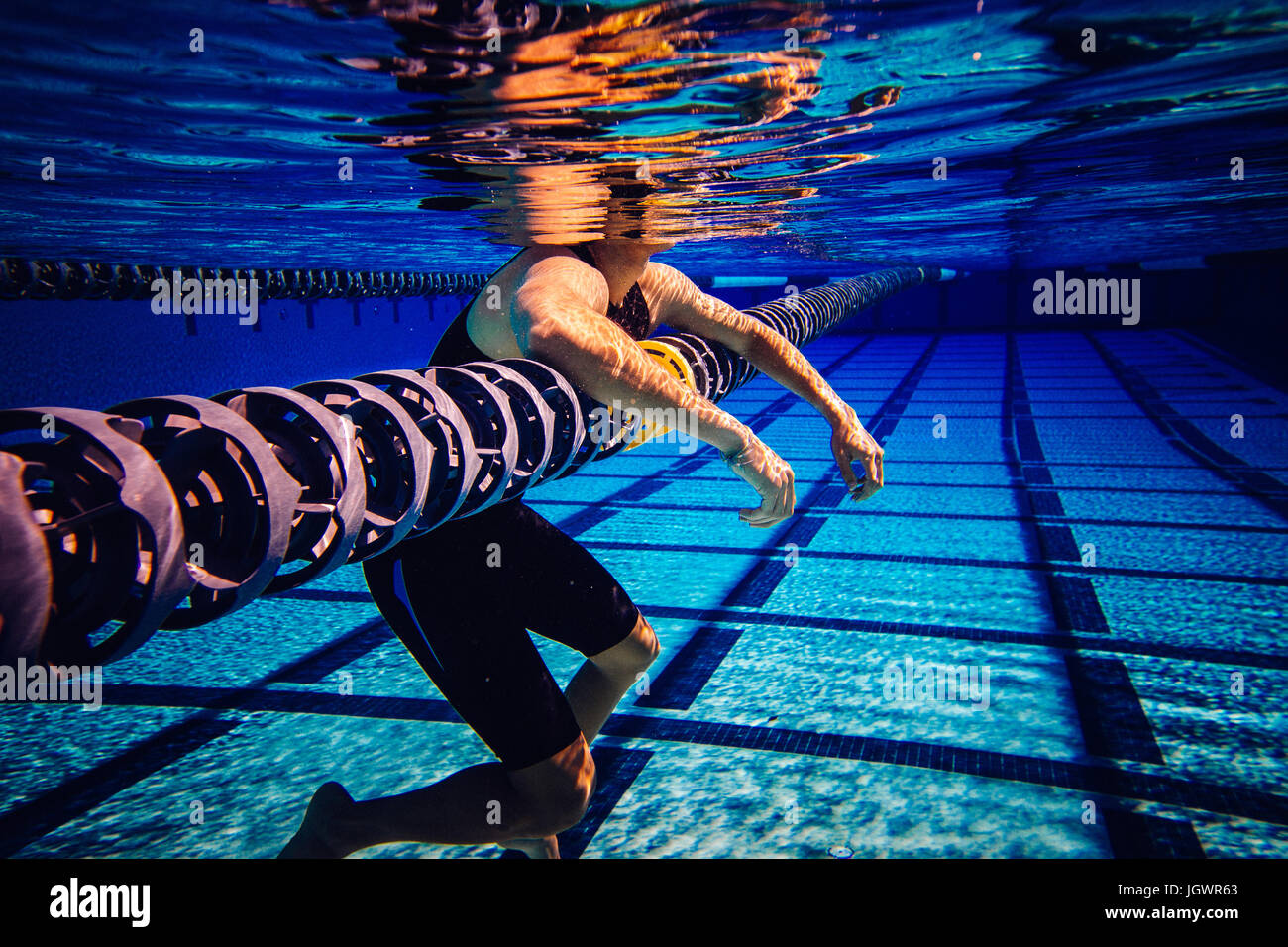 Swimmer resting on lane divider in pool