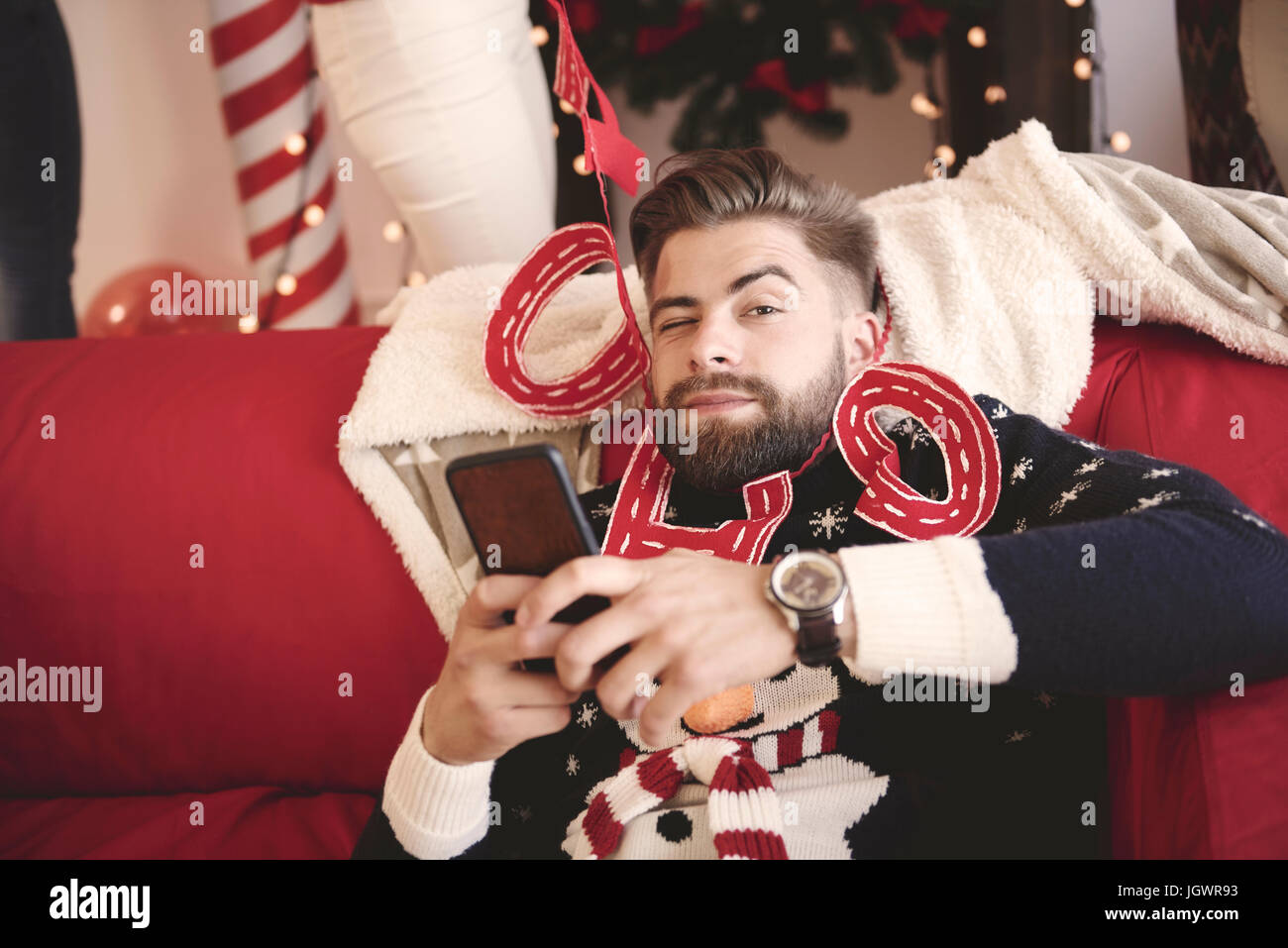Portrait of young man wrapped in christmas decorations at christmas party Stock Photo