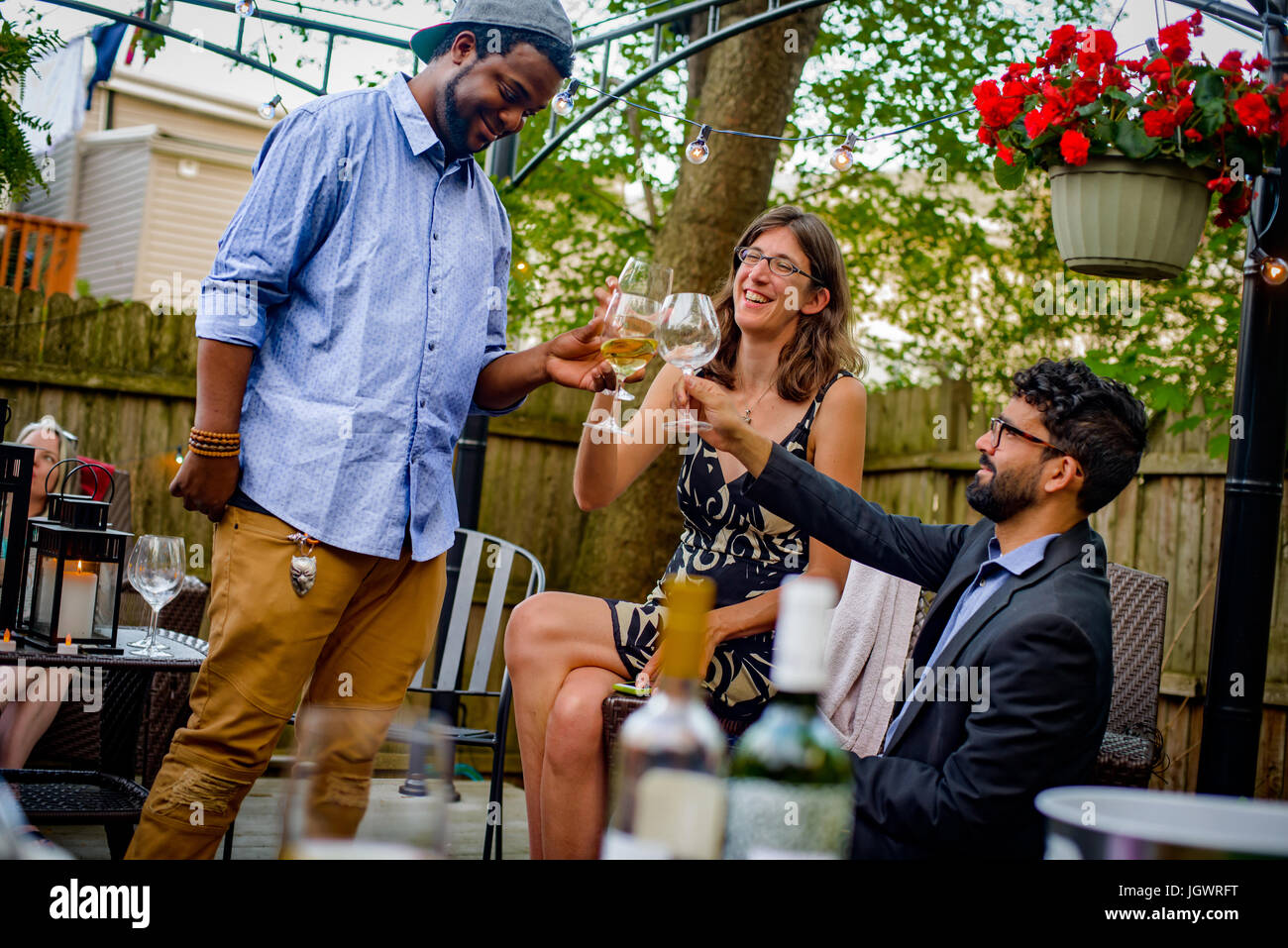 Three people at garden party, holding wine glasses, making a toast Stock Photo