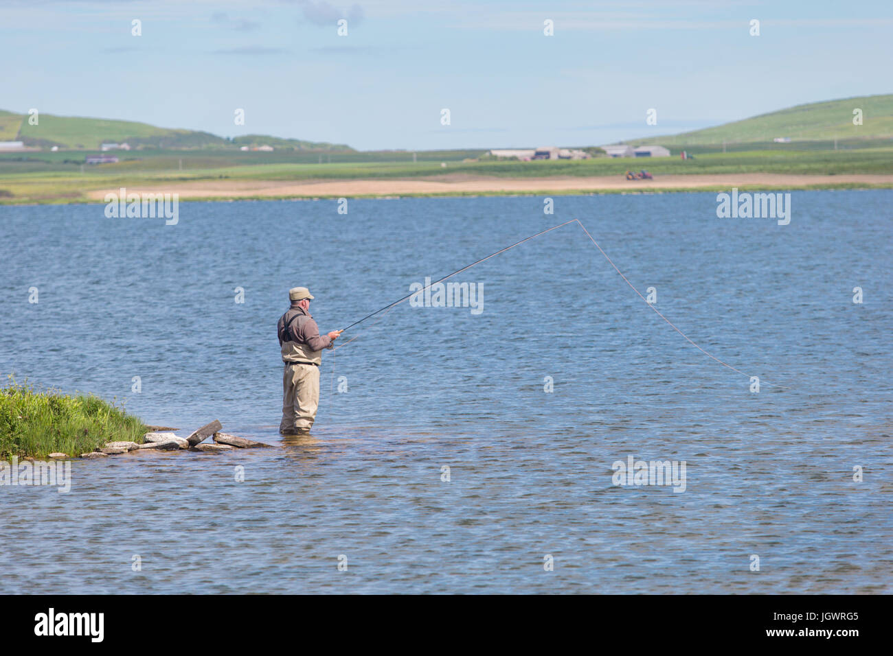 Man fly fishing in a loch in Orkney Scotland UK Stock Photo