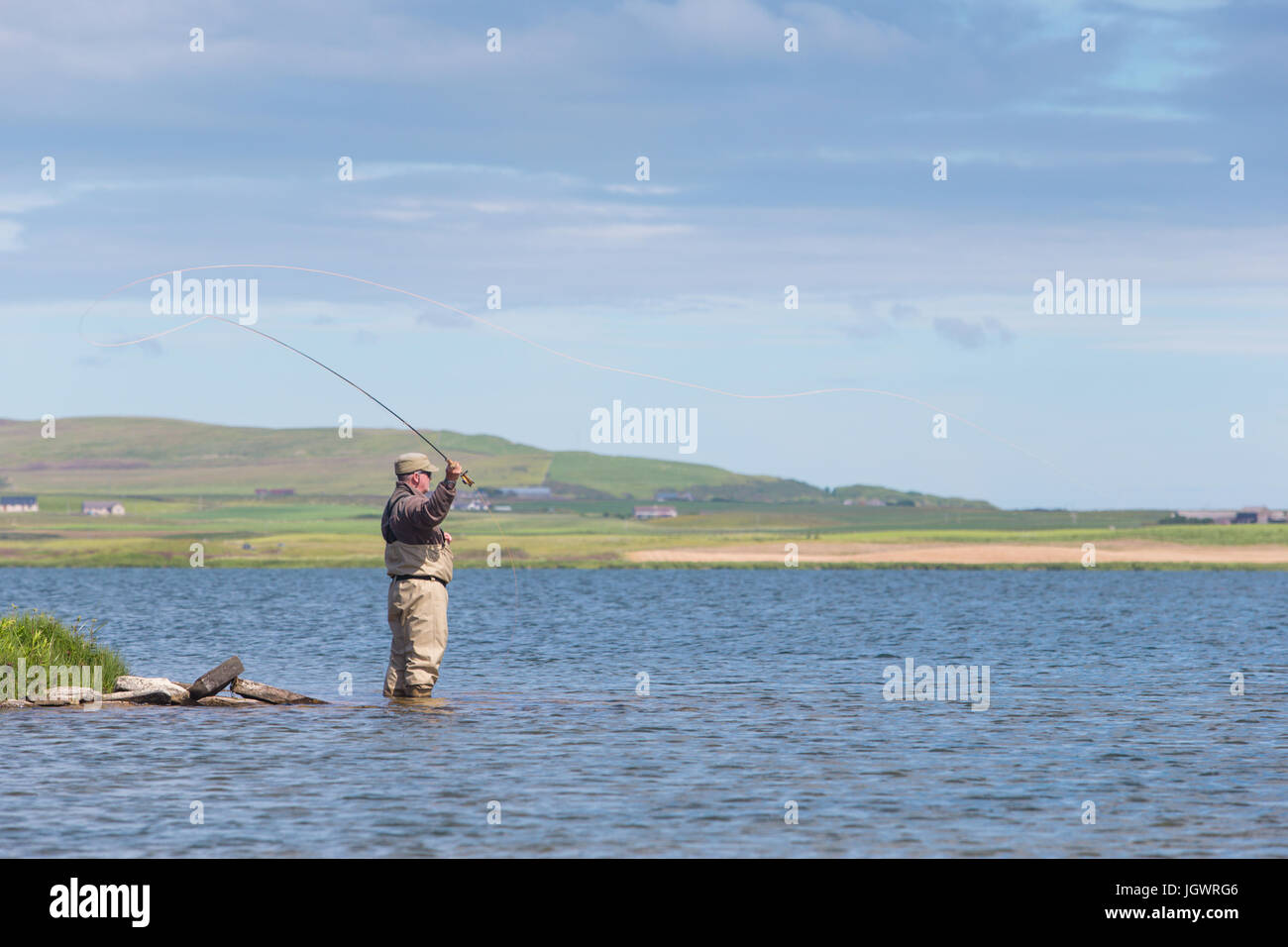 Man fly fishing in a loch in Orkney Scotland UK Stock Photo