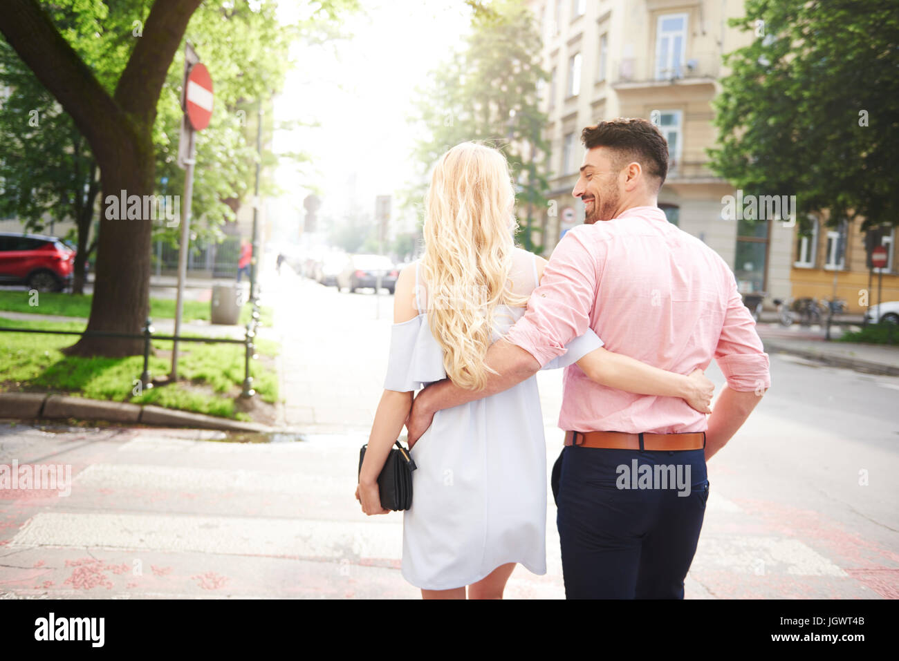 Rear view of couple walking in street arms around each other Stock ...