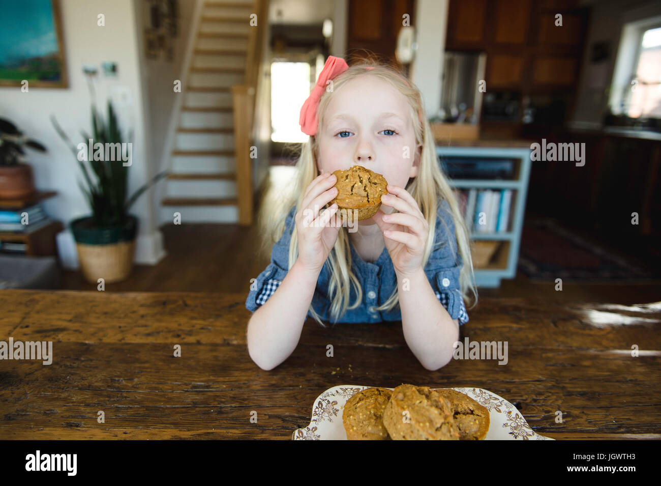 Portrait of girl eating muffin at kitchen table Stock Photo Alamy