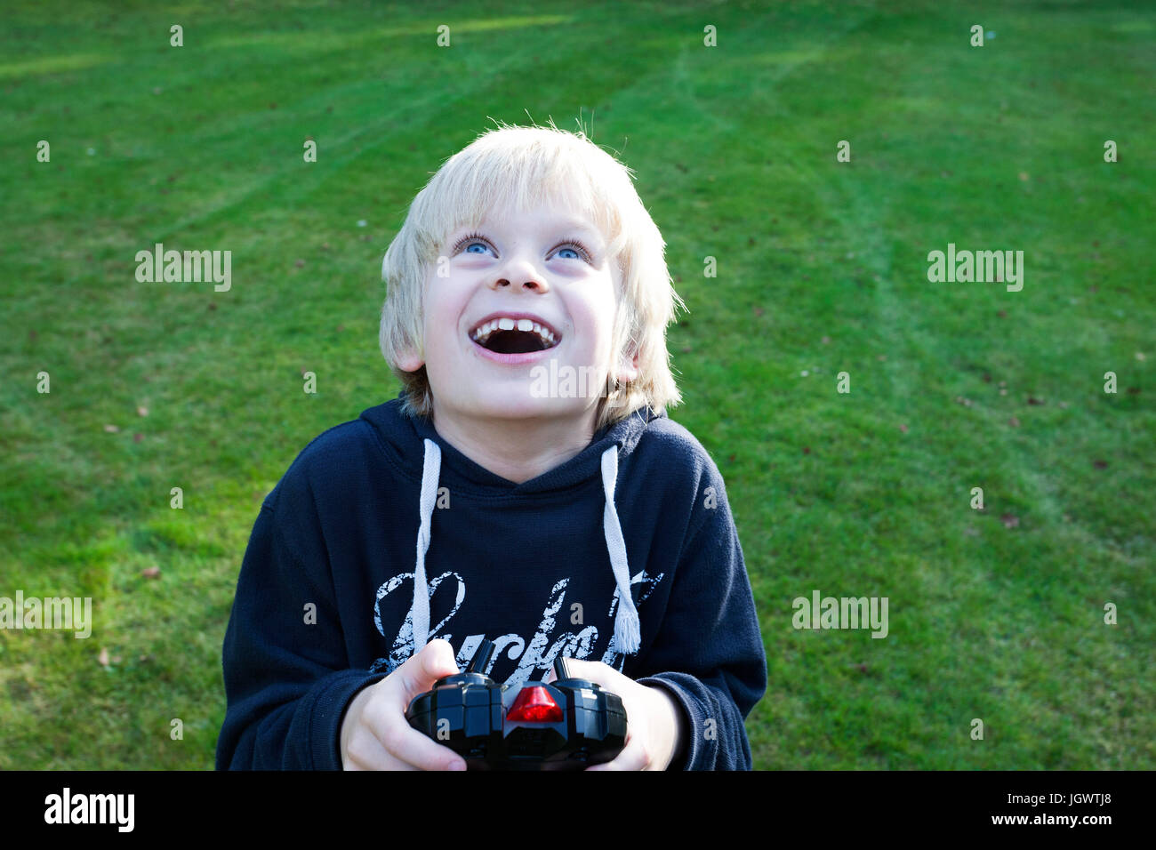 Boy holding remote control looking up smiling Stock Photo