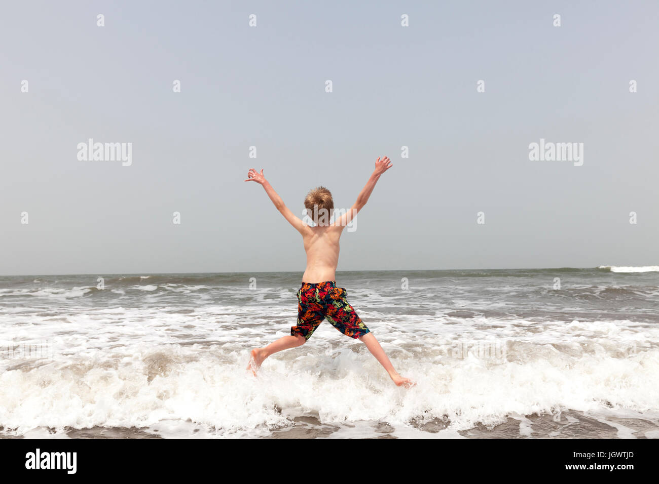 Rear view of boy jumping in sea, Goa, India, Asia Stock Photo