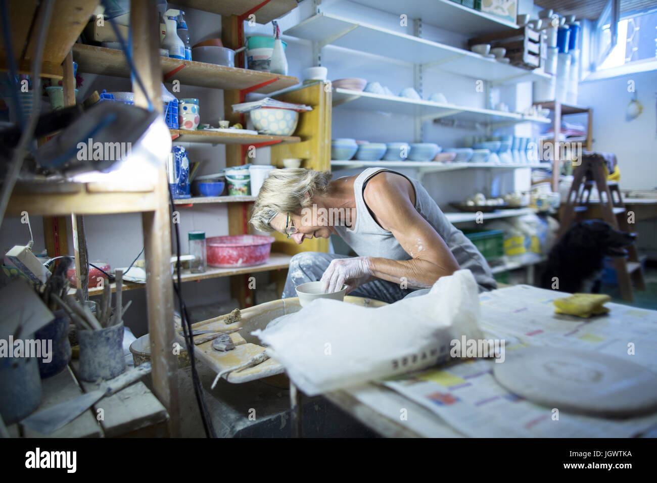 Senior woman in pottery workshop, at potters wheel, making bowl Stock Photo