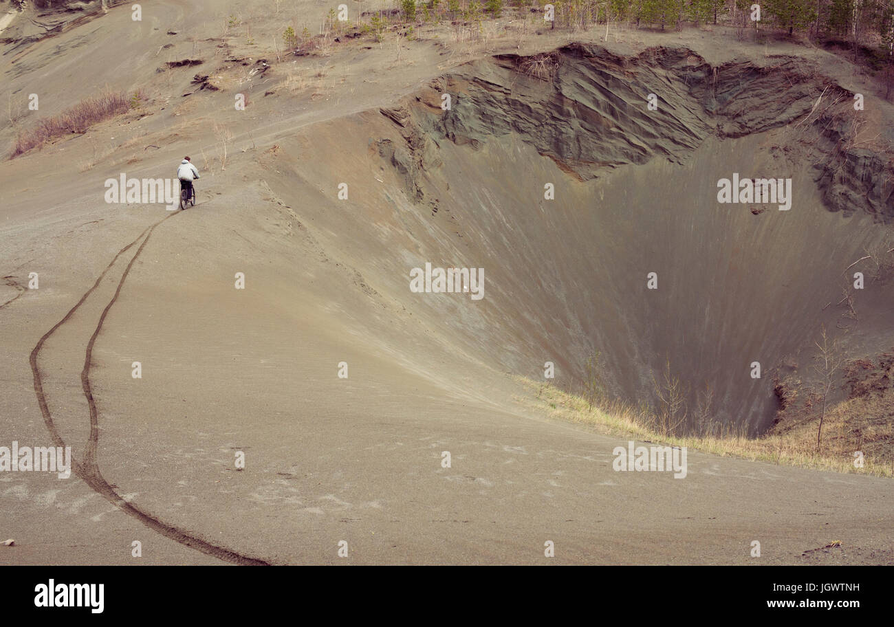 Distant view of male mountain biker mountain biking down quarry hill Stock Photo