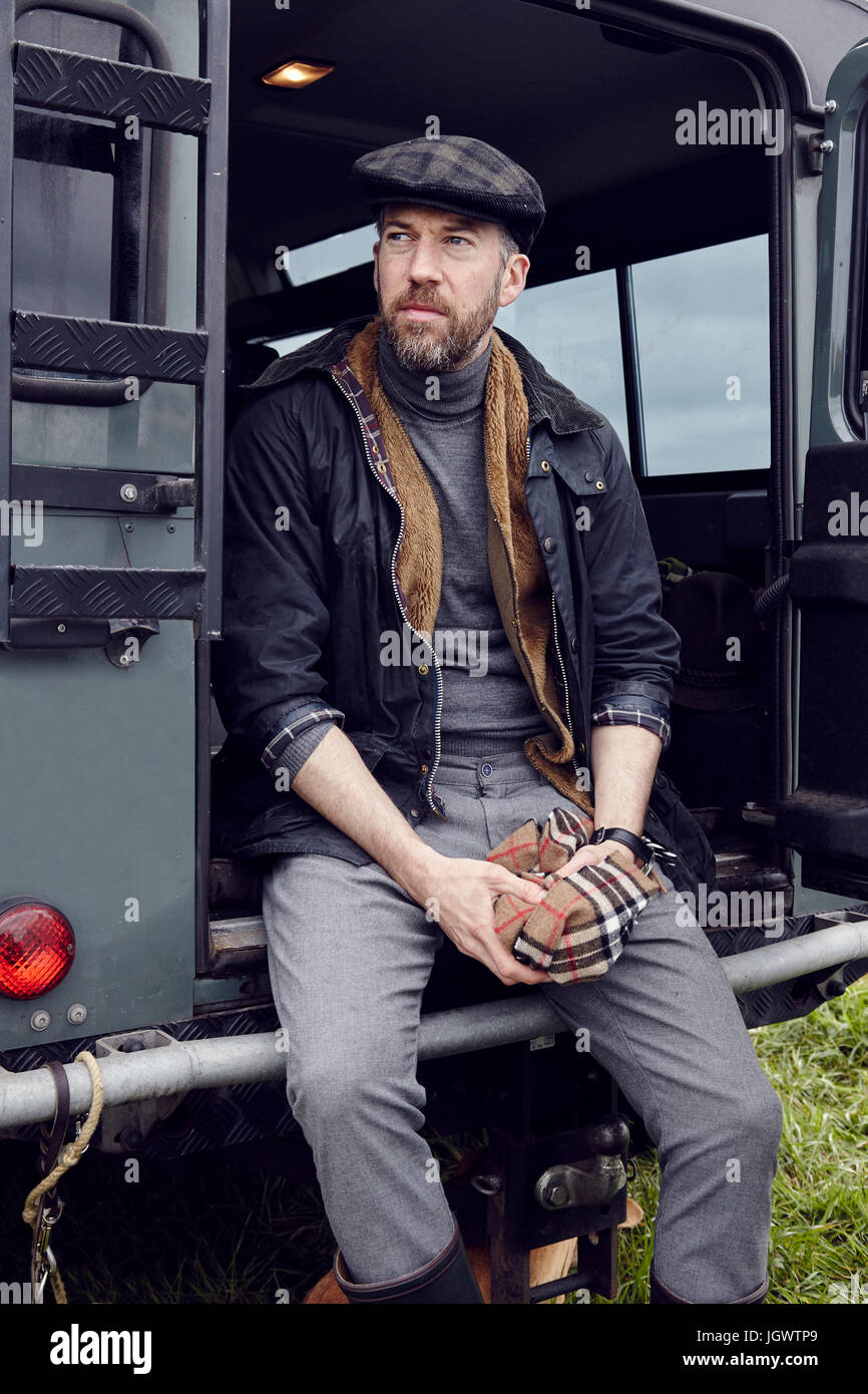 Man in outdoor clothes looking out from back door of off road vehicle Stock Photo
