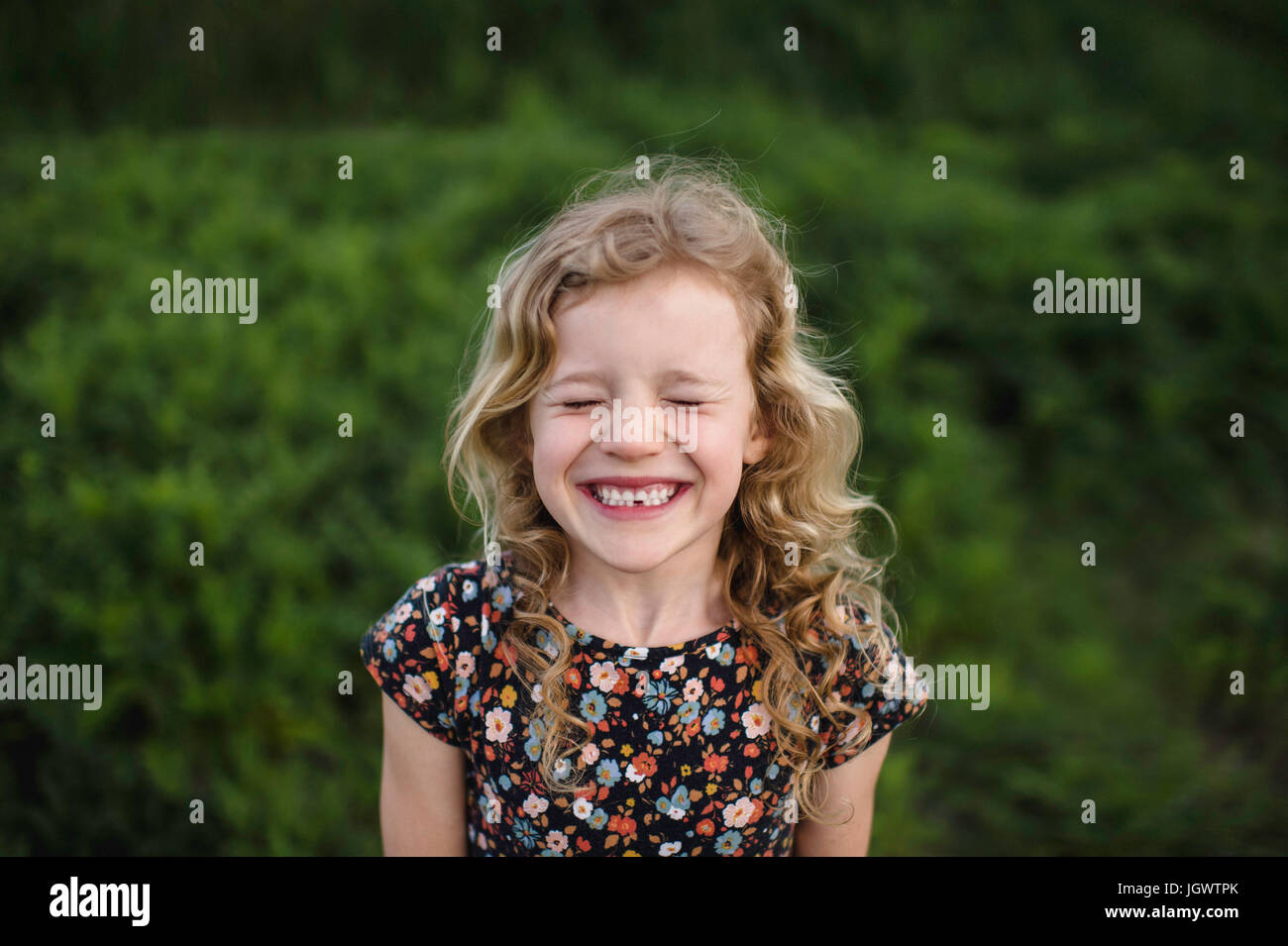 Portrait of girl with wavy blond hair and missing tooth in field Stock Photo