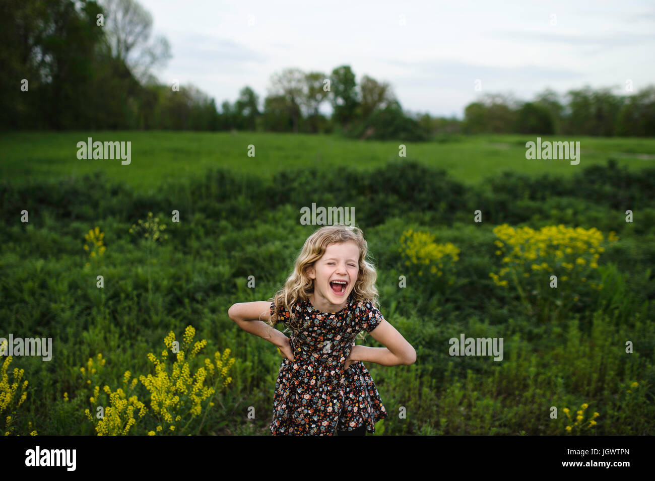 Portrait of girl with wavy blond hair laughing in field Stock Photo