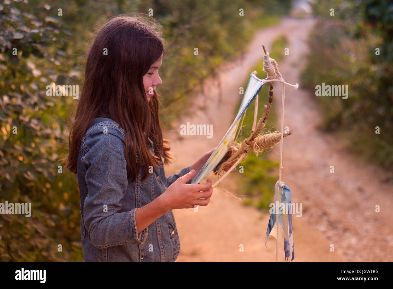 Teenage girl gazing at kite on dirt track Stock Photo