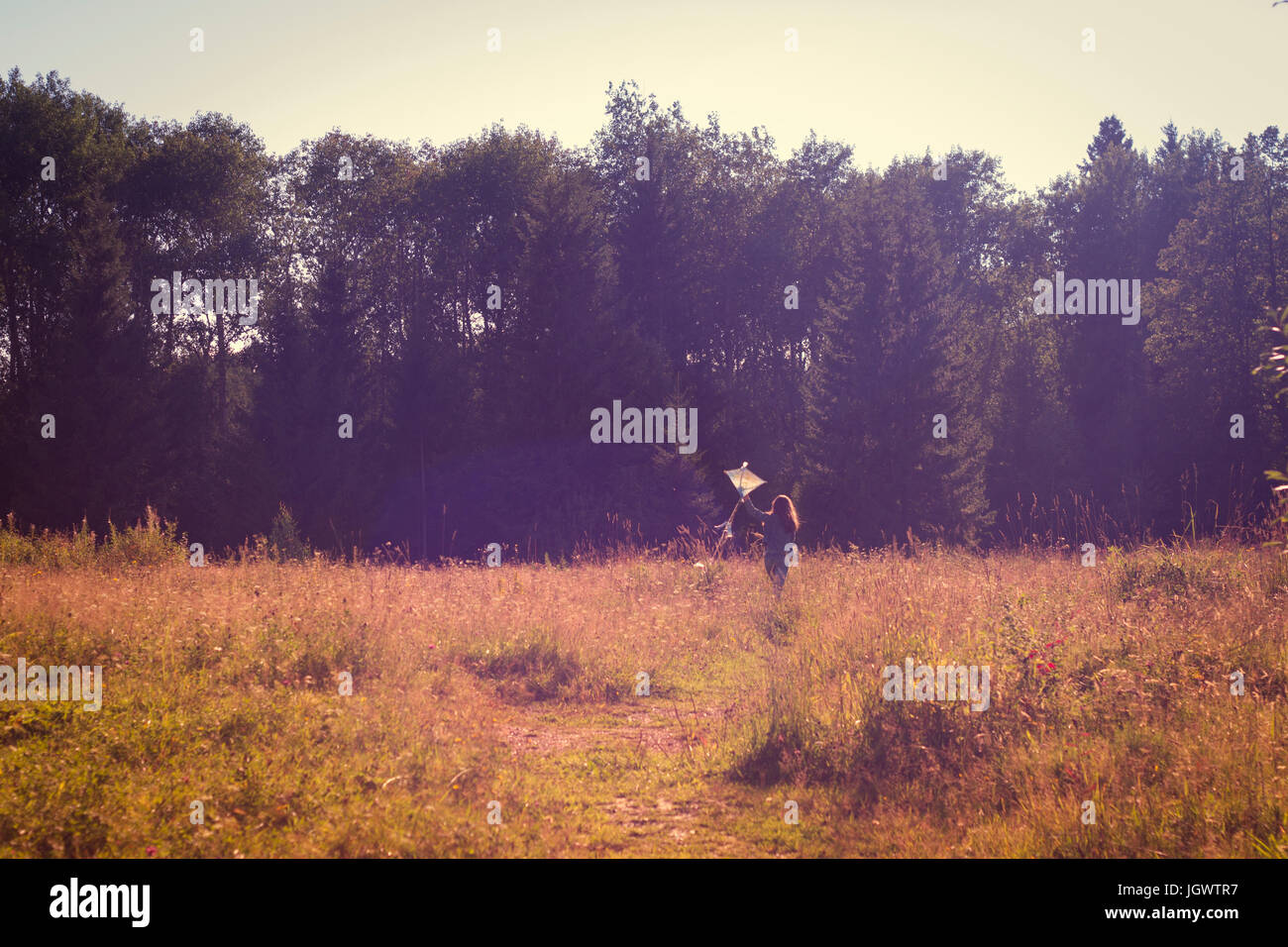 Rear view of teenage girl running with kite in field Stock Photo