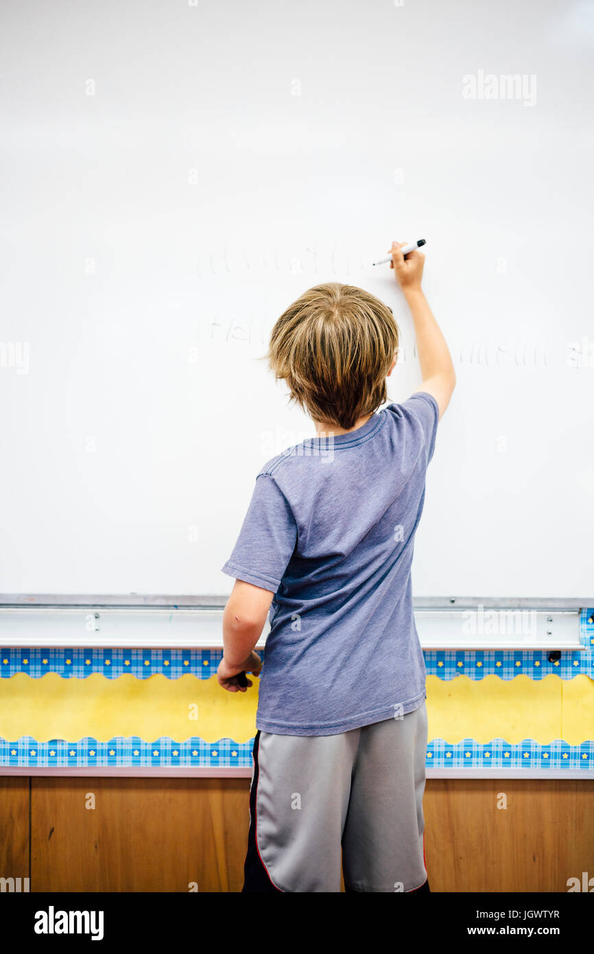 Young boy writing on whiteboard, rear view Stock Photo Alamy
