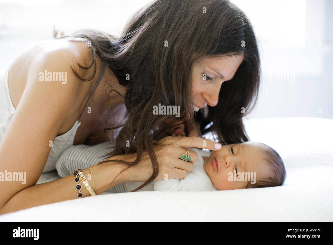 Mother leaning on bed, looking at newborn baby boy Stock Photo