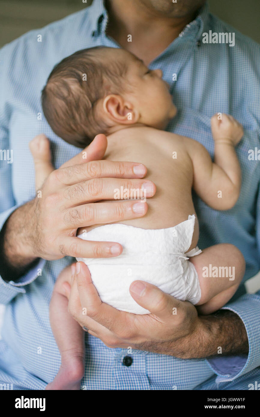 Father holding newborn baby boy to chest, mid section Stock Photo