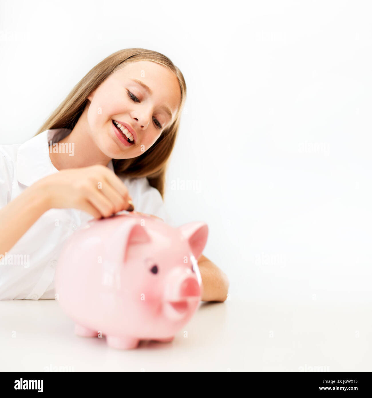 happy smiling girl putting coin into piggy bank Stock Photo - Alamy