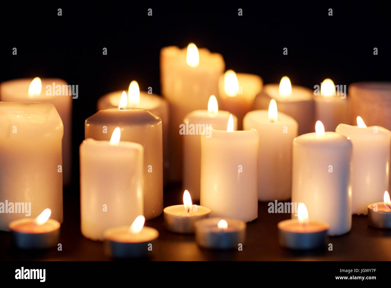 candles burning in darkness over black background Stock Photo - Alamy