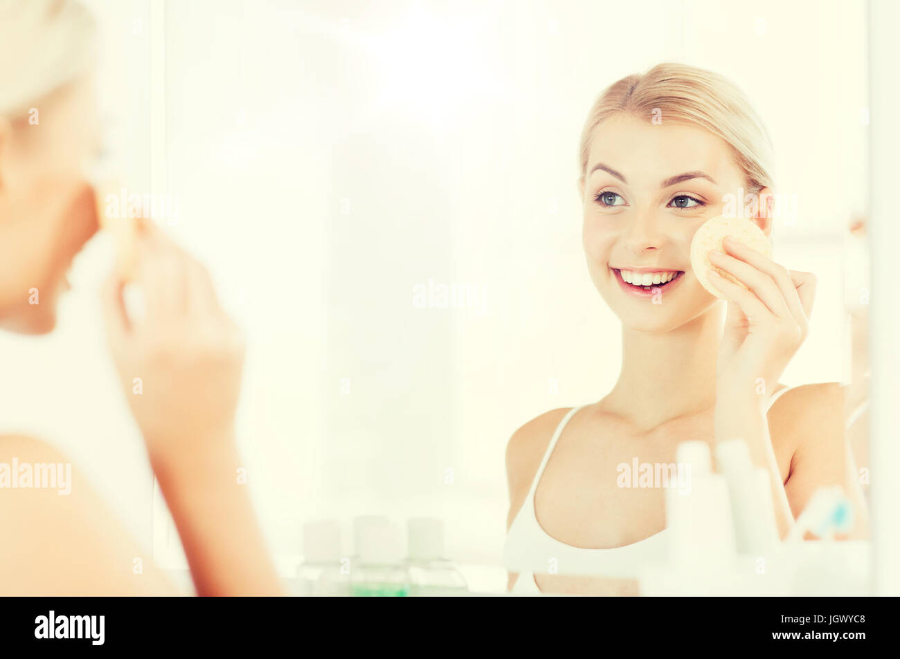 young woman washing face with sponge at bathroom Stock Photo Alamy