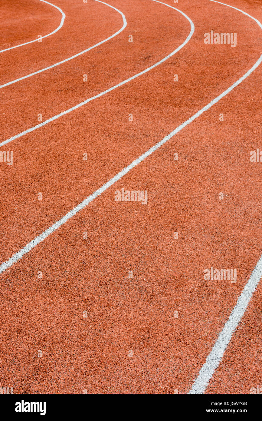 Close-up view of a red athletics track with white lines delimiting the lanes. Stock Photo