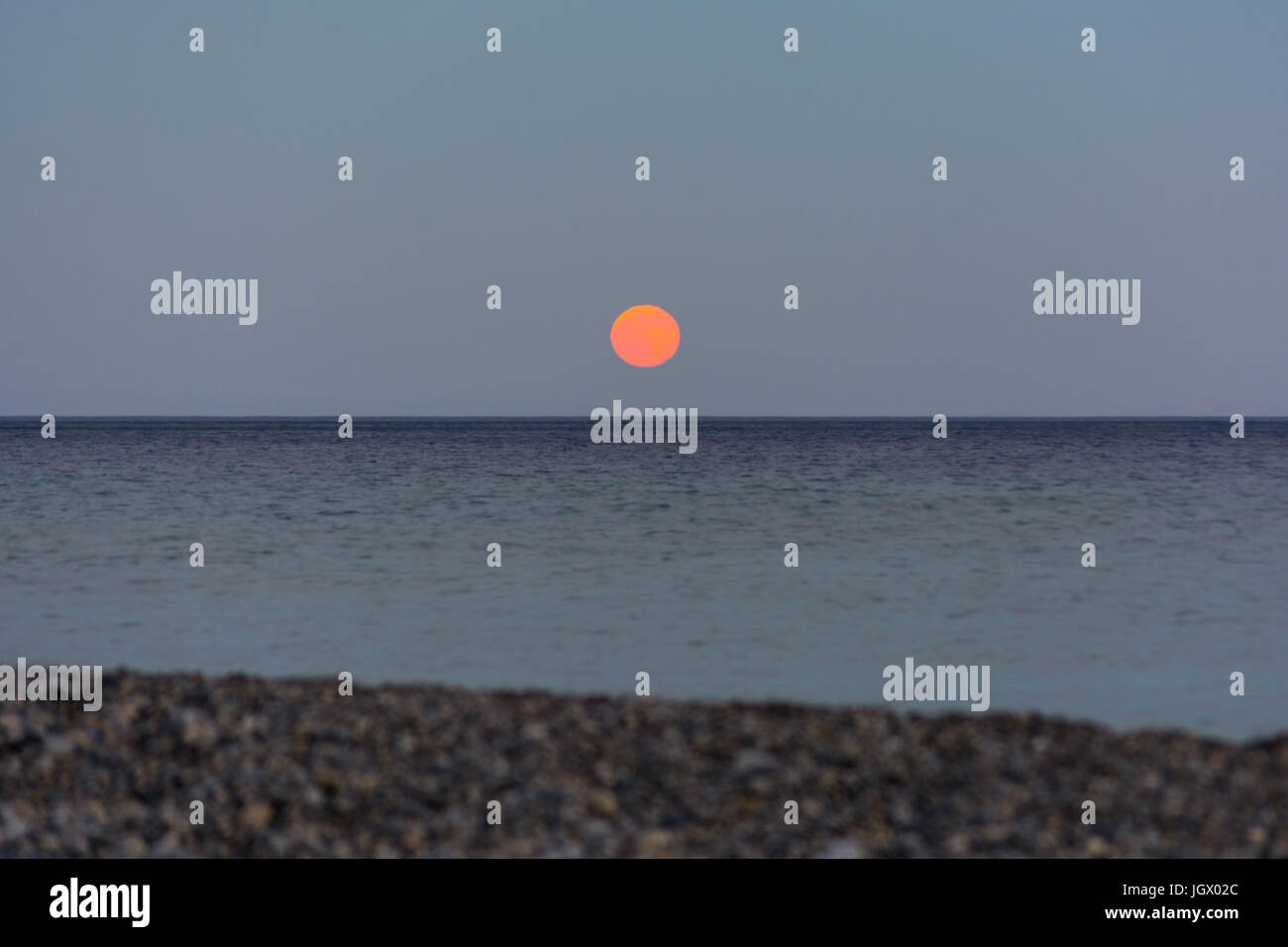 Orange moon rising over the sea horizon with copy space Stock Photo