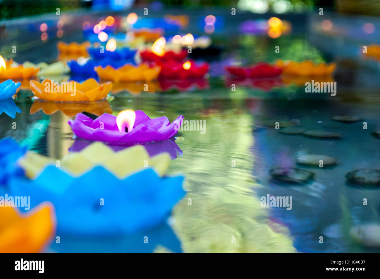 Lotus shape candle lit and float on water as sacred offering found in several religions and parts of the world. May be offering to gods, respect perso Stock Photo