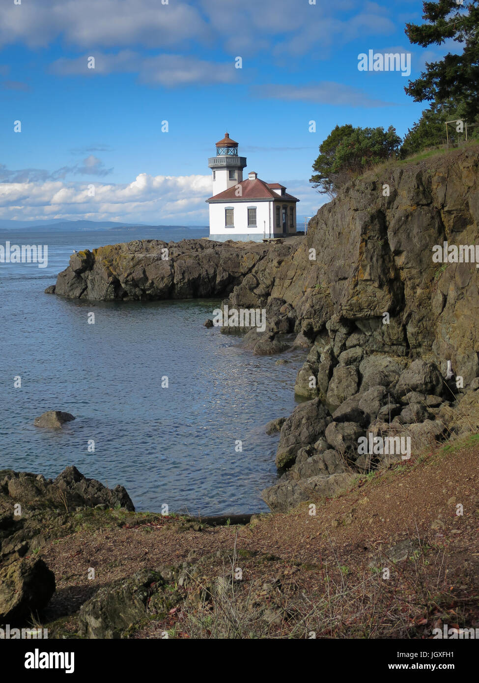 Lime Kiln Lighthouse on the west side of San Juan Island, Puget Sound, Washington State on a sunny day with blue sky, sea and white clouds. Stock Photo