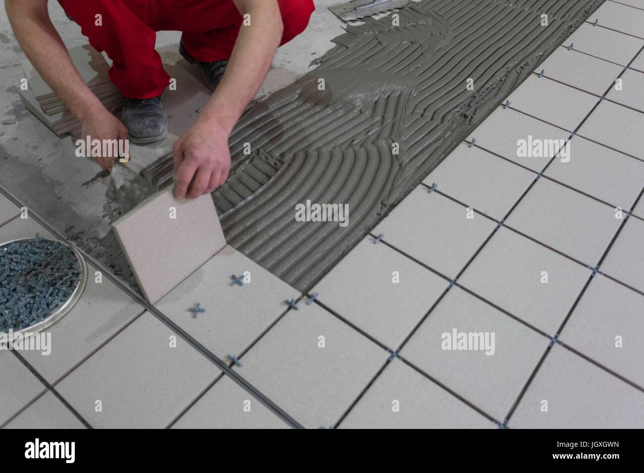 Masterfully gluing ceramic tiles in an industrial room Stock Photo