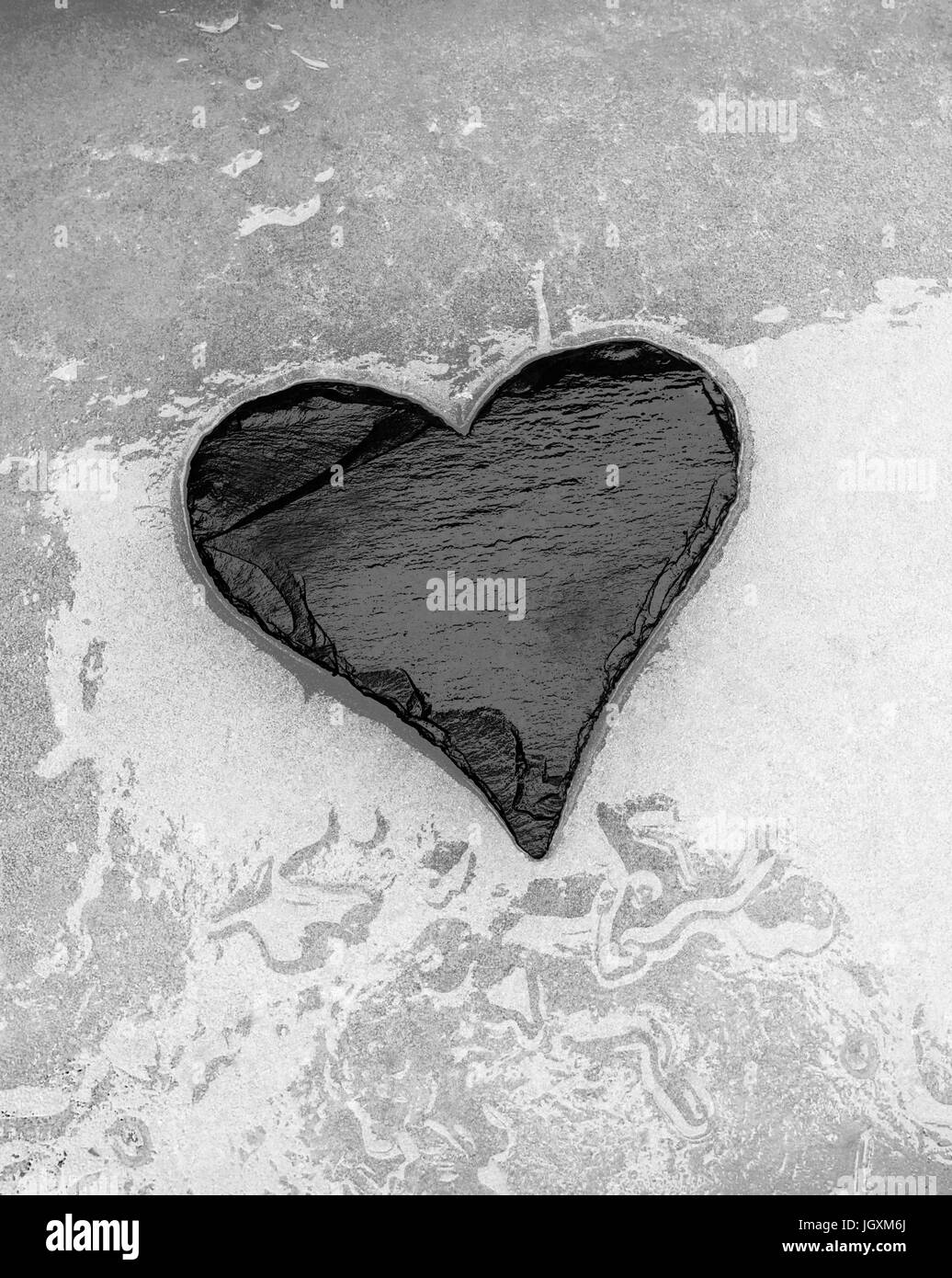 Slate heart lying on surface of melting ice Stock Photo