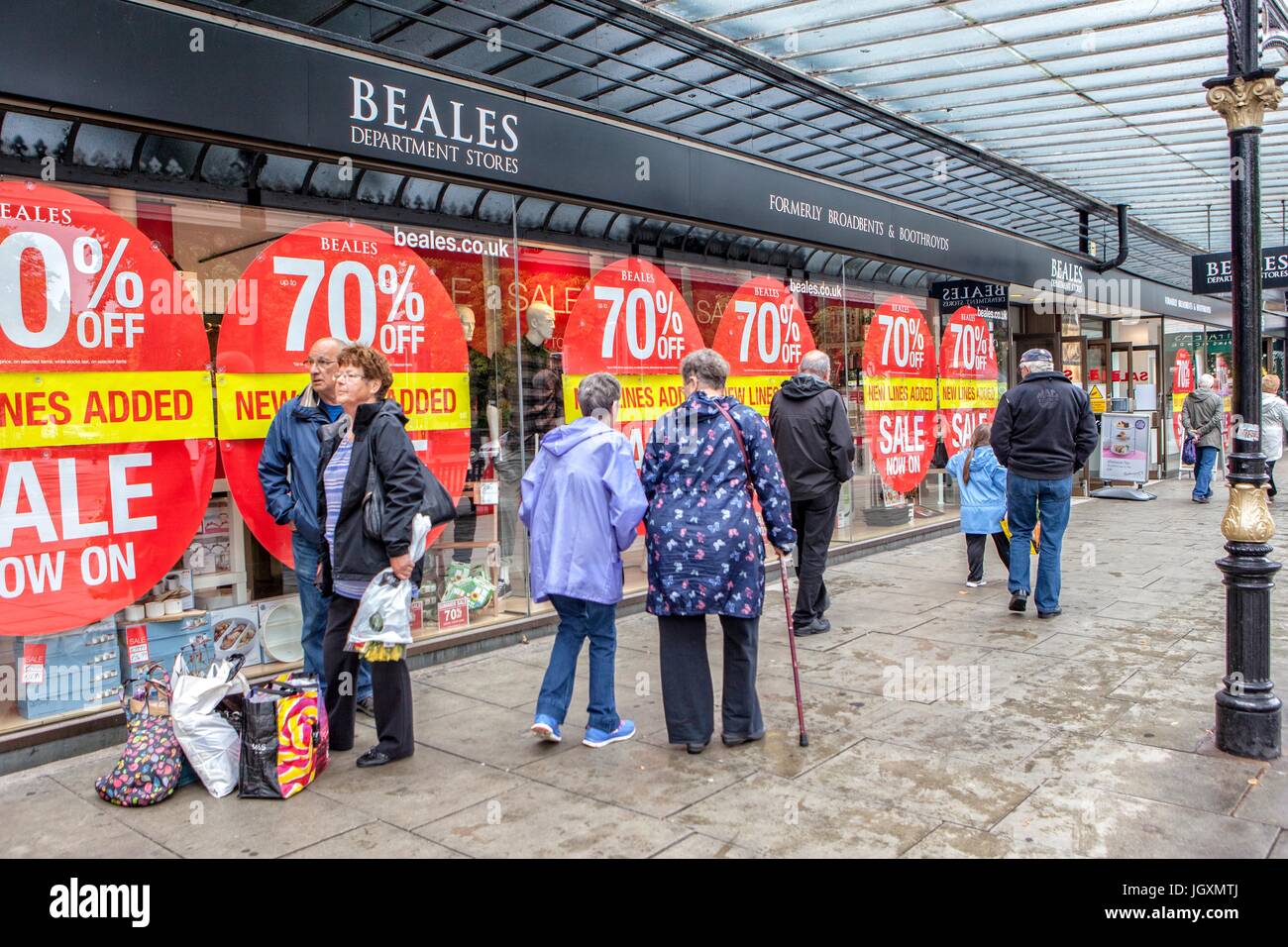 Red circular percentage off sales signs displayed on Beales department store window in Southport, Merseyside. Stock Photo