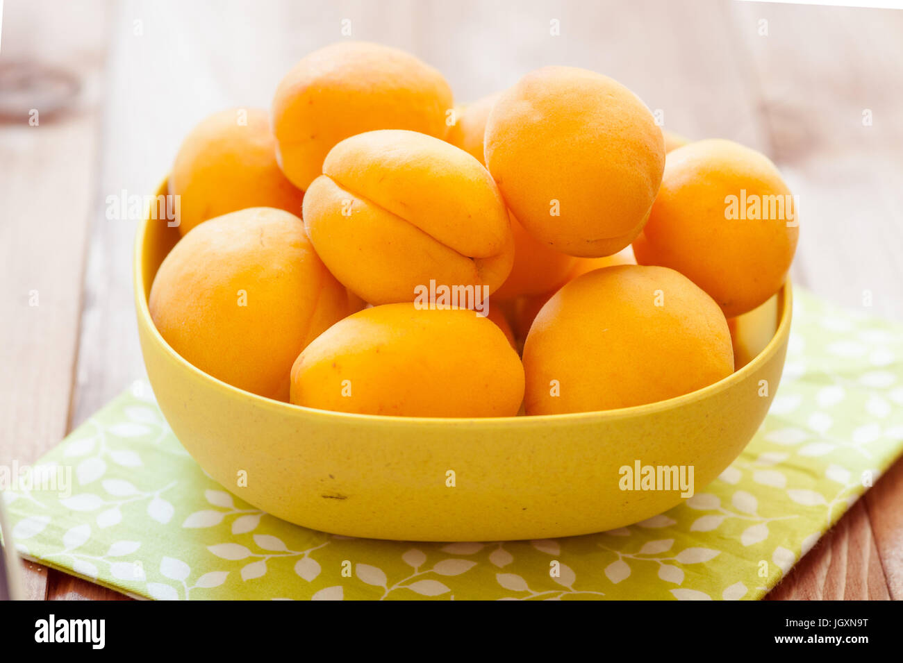 Heap of apricots in wooden bowl on table Stock Photo