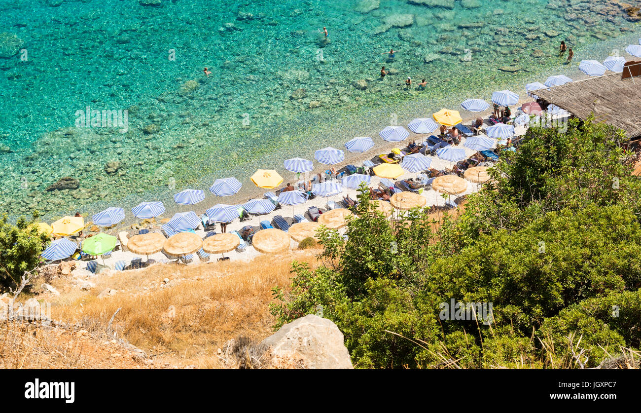 Looking down on the beach at Loutro, western Crete, Greece and the tops of the organised sunbeds and sun umbrellas. Stock Photo