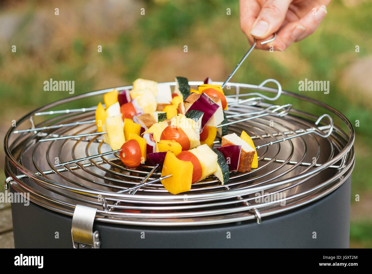 Man puts vegan kebabs with vegetables and tofu on a table grill. Stock Photo
