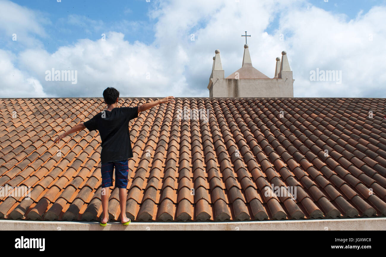 A boy in equilibrium on the roof of the monastery of Santa Maria dell'Isola, built on a little island on the beach of Tropea, famous place in Calabria Stock Photo