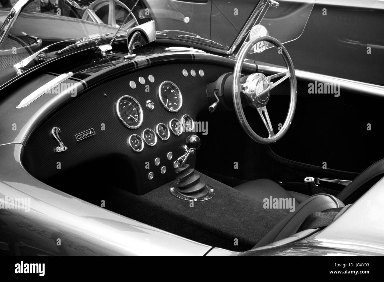 Monochrome of the drivers cockpit of an AC Cobra classic sports car showing dashboard instruments and steering wheel. Stock Photo